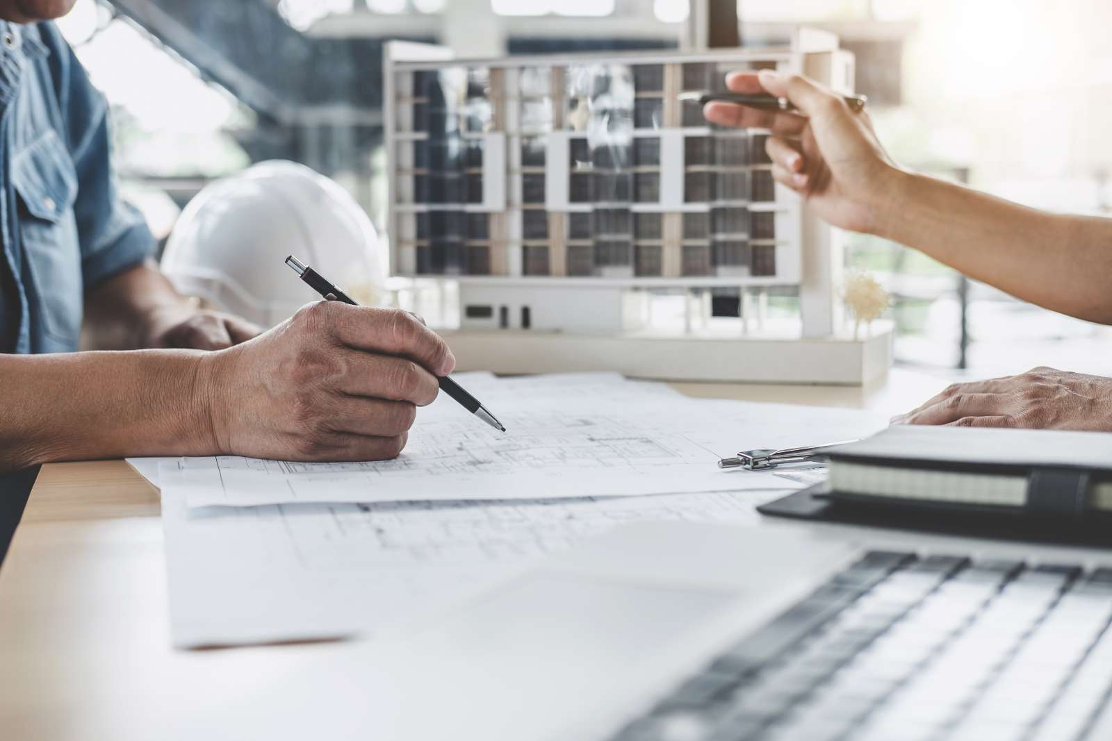 Architekten besprechen an einem Tisch ein Model und Baupläne